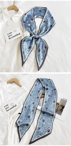 Close-up of light blue paisley silk twilly scarf styled on a white shirt collar