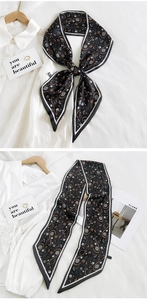 Close-up of black paisley floral silk scarf styled on a white shirt with elegant draping