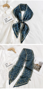 Close-up of a long navy silk scarf with gold vintage prints tied as a bow on a white shirt