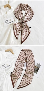 Detail of champagne letter pattern silk scarf tied on a white shirt in a chic setting