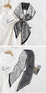 Macro detail of silk scarf featuring classic black and white paisley and polka dot patterns