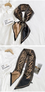 Detail of zebra pattern twilly scarf with brand lettering next to gold ring and card