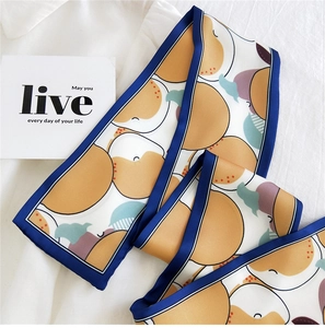 Détail d'un long foulard en soie avec motifs d'oranges et bordures bleu marine