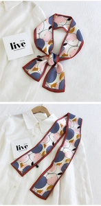 Détail d'un twilly en soie artistique avec bordure rouge sur une chemise blanche