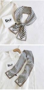 Détail d'un foulard en soie à rayures en V géométriques noir et blanc avec bordure kaki