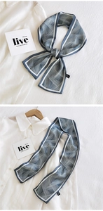 Détail d'un foulard en soie à motif géométrique noué en nœud sur un col blanc