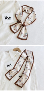 Détail d'un foulard en soie à motif lapin avec bordure marron sur une chemise blanche
