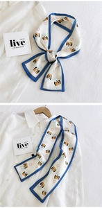 Détail d'un foulard en satin blanc avec bordure bleue et motifs de lapin sur chemise