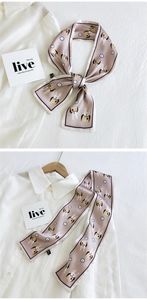Détail d'un foulard en soie rose avec imprimé lapin et horloge noué en ruban