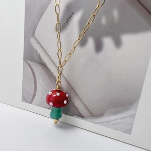 Detailed macro view of a red mushroom pendant on a gold oval link chain necklace