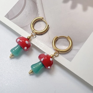 Detail of red mushroom hoop earrings with white dots and gold-plated hooks on white card