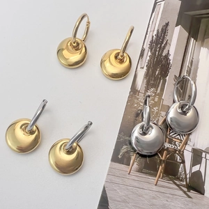 Three pairs of modern round gold and silver dangle earrings on a lifestyle magazine background