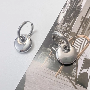 Close-up of silver hoop earrings with high-polish mirror finish round charms