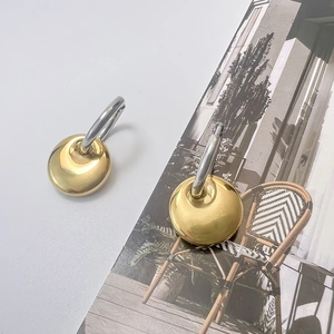 Detail of high-polish gold disc earrings with silver hoops on minimalist fashion booklet