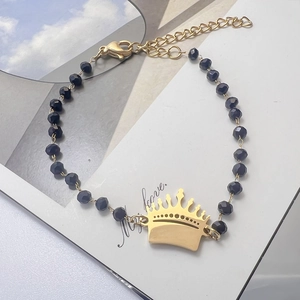 Detail of beaded bracelet with black beads, golden crown charm and lobster clasp