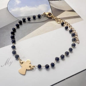 Detail of beaded bracelet with black faceted beads and a golden angel charm pendant