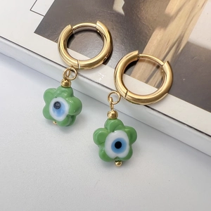 Detailed view of gold hoop earrings with green flower charms and evil eye enamel center