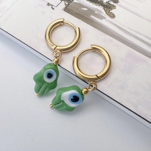 Détail de boucles d'oreilles main de fatma dorées avec pendentifs en verre vert