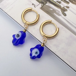 Détail de boucles d'oreilles Main de Fatma dorées avec pendentif Mauvais Oeil en verre