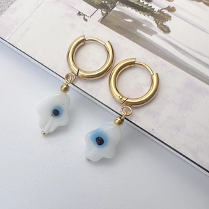 Détails de boucles d'oreilles main de Hamsa dorées avec pendentifs oeil bleu