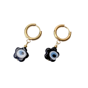 Gold hoop earrings featuring black flower pendants with blue evil eye charms on white base