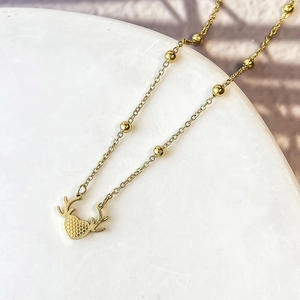Dettaglio della collana cuore corna d'oro con texture a nido d'ape su marmo