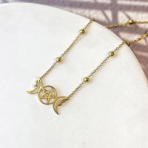 Dettaglio della collana in acciaio dorato con ciondolo a pentagramma e luna e piccole perle