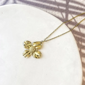Detail of a vintage golden flower pendant with textured petals on a marble display