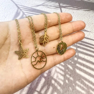 Détail de quatre colliers en acier inoxydable doré avec pendentifs inspirés de la nature