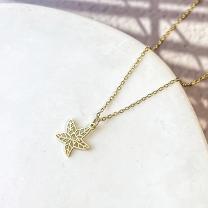 Élégant collier en acier inoxydable doré avec pendentif étoile sur fond de marbre