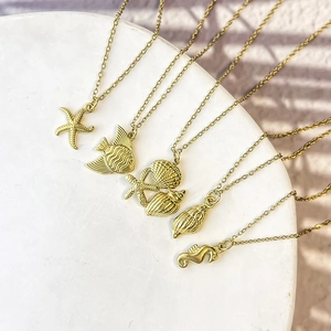 Detail view of gold-plated starfish, seashell, and seahorse charms on fine necklaces