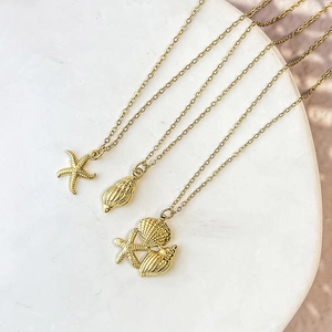 Detail of three gold plated stainless steel necklaces with starfish and seashell pendants