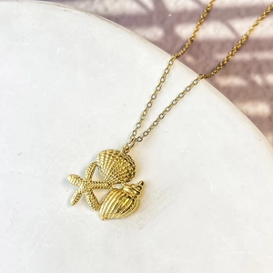 Detail of gold seashell, starfish and conch charms on a minimalist beach necklace