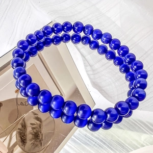 Detail shot of deep blue cat eye stone beads on a double-layer bracelet with mirror reflection
