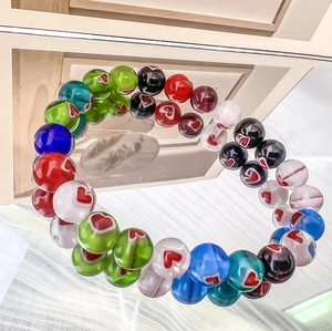 Macro shot of colorful glass beads with red heart patterns on a beaded elastic bracelet