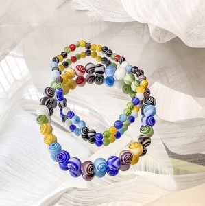 Bunte Millefiori-Glasperlenarmbänder mit Spiralmuster auf weißem Stoffhintergrund