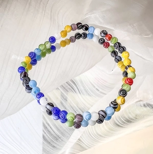 Detailansicht bunter Millefiori-Glasperlen mit Spiralmustern auf einer Glasoberfläche