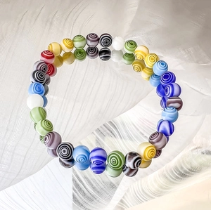 Detailansicht bunter Millefiori-Glasperlen mit Spiralmuster auf einem Spiegel