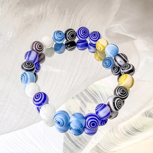 Detailaufnahme bunter Millefiori-Glasperlen mit Spiralmuster auf einem elastischen Armband