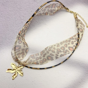 Detail of leopard print ribbon necklace with gold flower pendant and lobster clasp