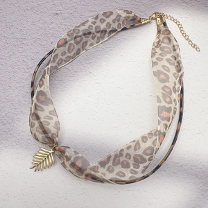 Detail of leopard print silk ribbon wrapped on ring with golden leaf pendant necklace