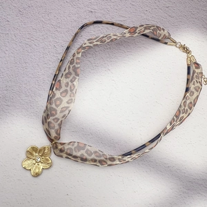 Detail of leopard print fabric cord and gold flower pendant with sparkling center zircon