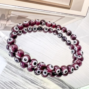 Dettaglio di perline Evil Eye viola intenso da 6 mm su braccialetti elastici con riflesso