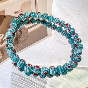 Detail of green handmade glass beads with floral patterns on a bohemian elastic bracelet