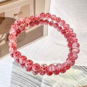 Detail of pink glass beaded bracelet with red daisy flower patterns and elastic band