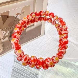 Detailed close-up of handmade glass beaded bracelets with red floral daisy pattern beads