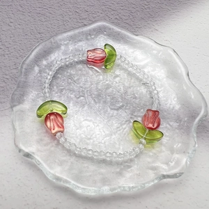 Detail shot of a beaded tulip bracelet with transparent glass beads and red floral charms