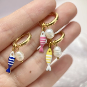 Tre orecchini a pesce in oro con perle d'acqua dolce e smalto colorato nel palmo della mano