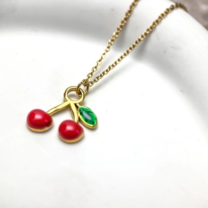 Élégant collier en chaîne dorée avec pendentif cerise rouge et détail de feuille