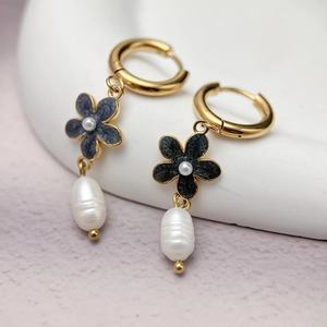 Detailed shot of gold cherry blossom earrings with black petals and baroque pearls